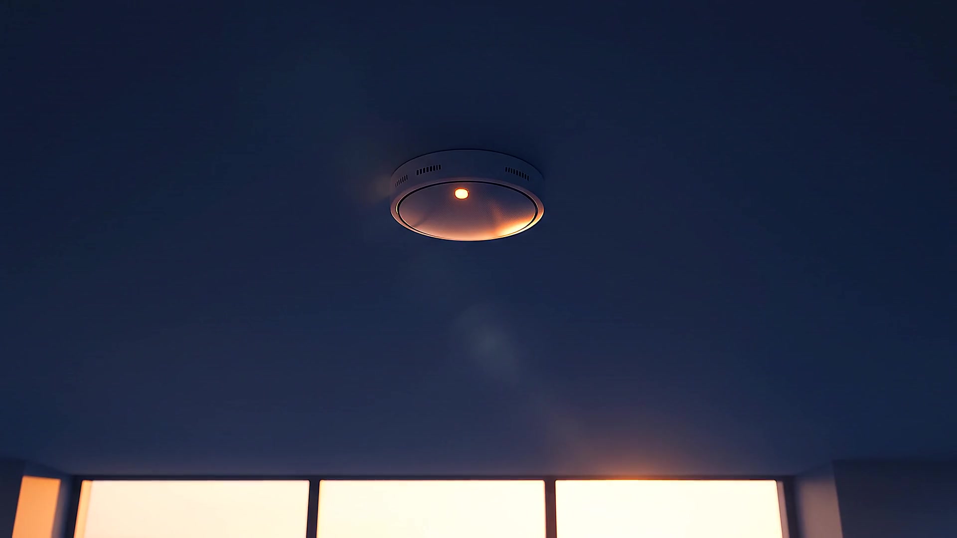 A ceiling smoke detector at night, its amber light softly on